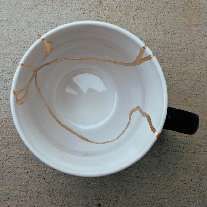 Photo of white mug with cracks filled with gold inlay
